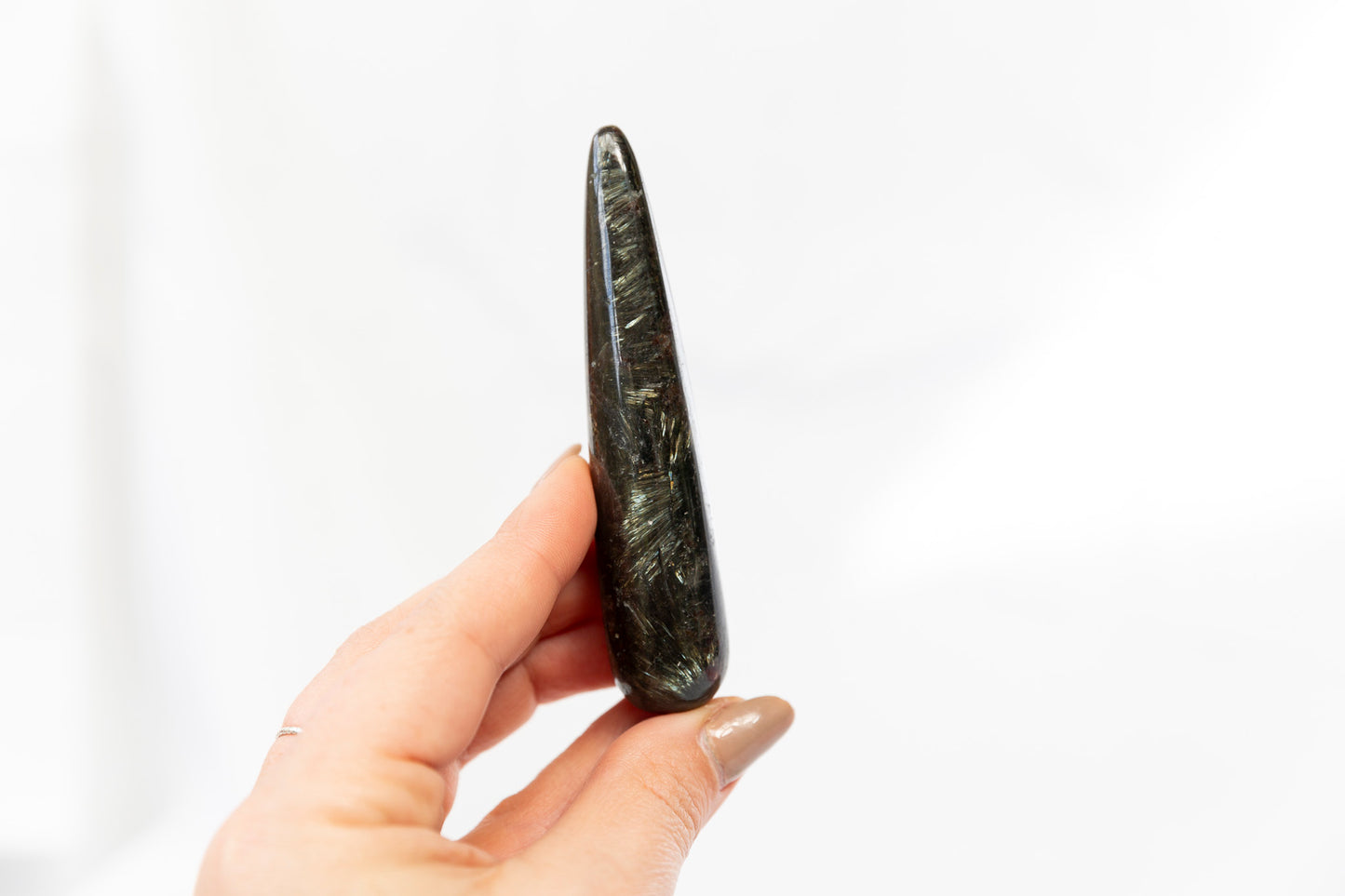 Hand holding a dark stone or crystal against a white background
