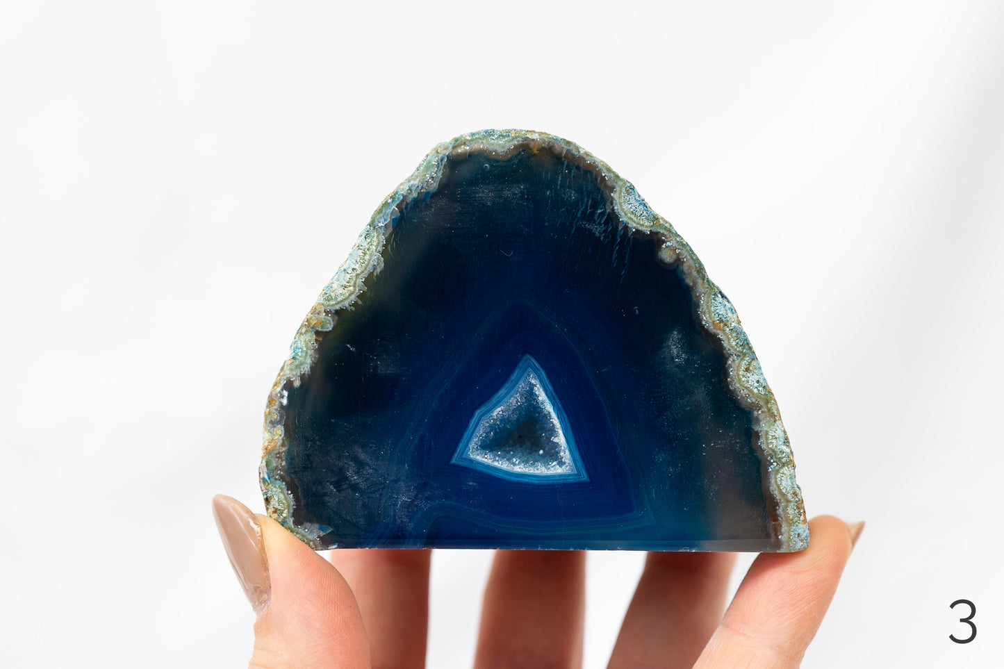 Geode crystal held by a hand against a white background