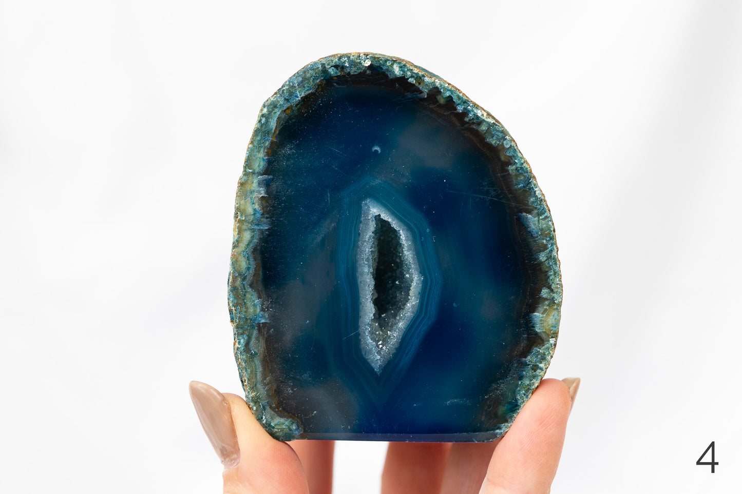 Hand holding a blue agate stone against a white background