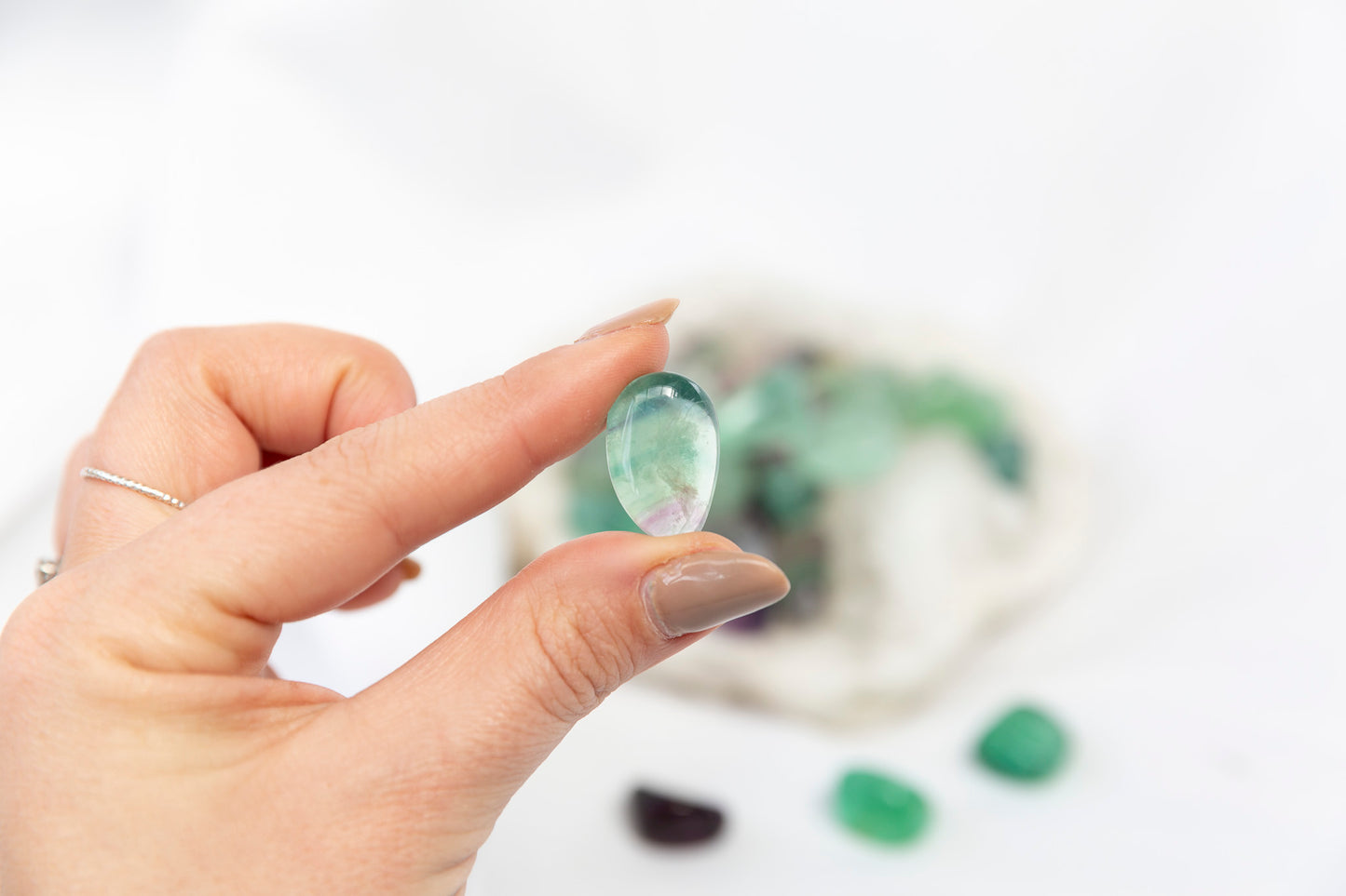 Hand holding a green gemstone with a blurred background