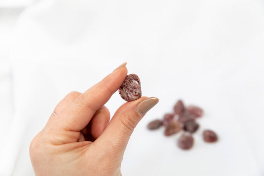 Hand holding a red crystal against a white background with other red crystals