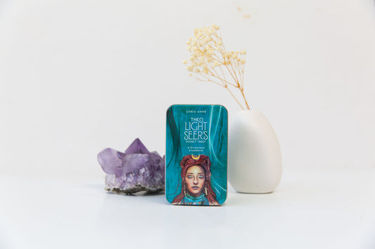 The Light Seer's Tarot Pocket Deck with an amethyst crystal and a bud vase holding dried baby's breath flowers