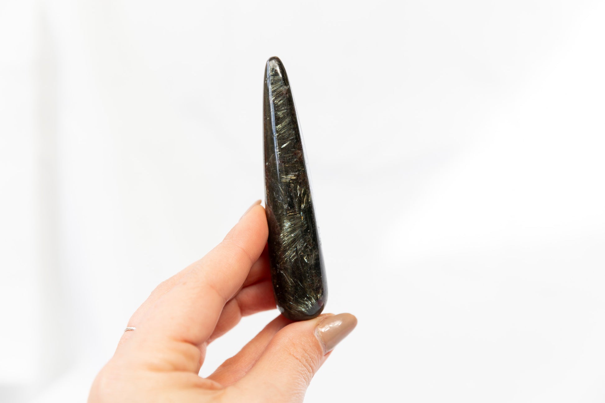 Hand holding a dark stone or crystal against a white background