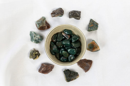 Small bowl filled with dark green stones on a light background