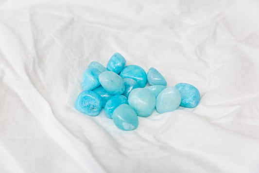 Blue aragonite tumblestones on a white fabric background