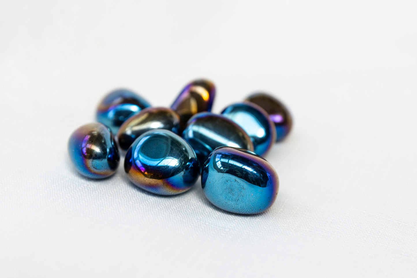 Blue titanium aura quartz tumblestones on a white background