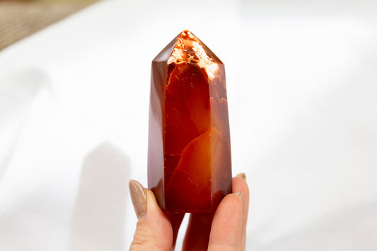 Hand holding a red crystal against a white background