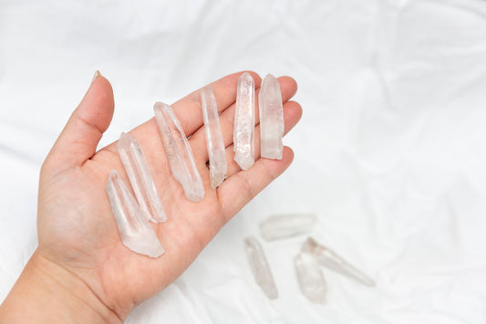 Hand holding clear quartz crystal points on a white background