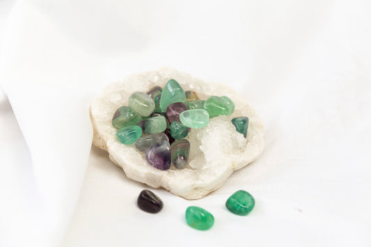 Colorful fluorite gemstones on a white stone with a white background