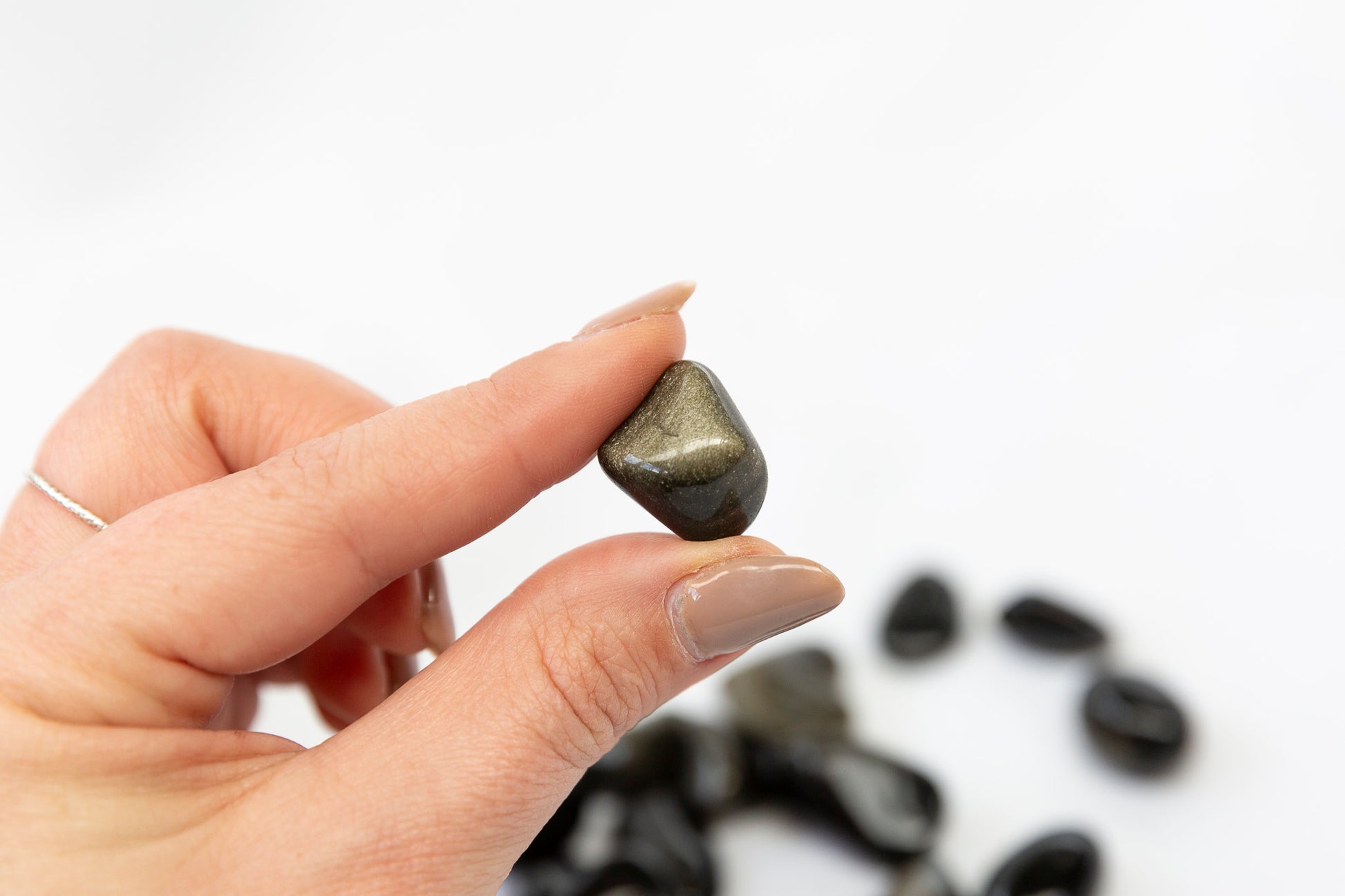 Hand holding a small black stone with a blurred background