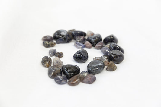 Round iolite tumblestones arranged in a circle on a white background