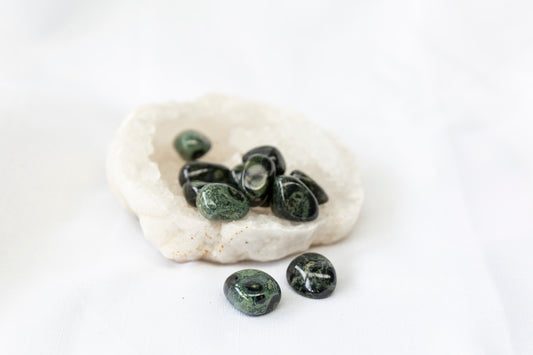 Green stones on a clear quartz geode against a white background