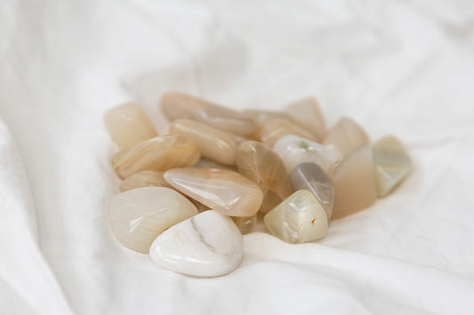Collection of polished moonstone crystal tumblestones on a white fabric background
